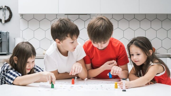 Des amis réunis autour d’une table choisissent un jeu de plateau parmi plusieurs boîtes.